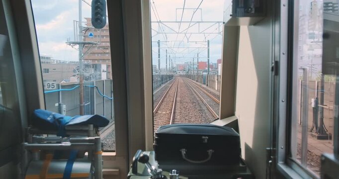 Moving metro rail view, throught cabin transport. Driver perspective from front cabin of japanese train moving along railway tracks. Urban landscape, continuous journey through Tokyo city. No people