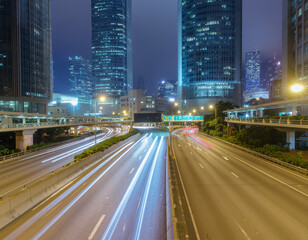 Obraz premium A long exposure photograph captures the vibrant light trails of vehicles speeding along a highway at night, framed by towering skyscrapers in a bustling urban landscape.