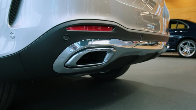 Close-up of car dual exhaust tips and rear diffuser with chrome surrounds on silver bumper. Premium luxury SUV rear performance detail for automotive and motorsport editorial content.