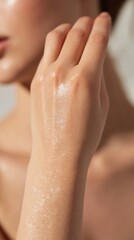 Fototapeta premium Close-up of a woman's hand applying perfume to her wrist in natural light