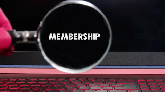 A magnifying glass slides over a dark digital screen, bringing the word MEMBERSHIP into sharp focus