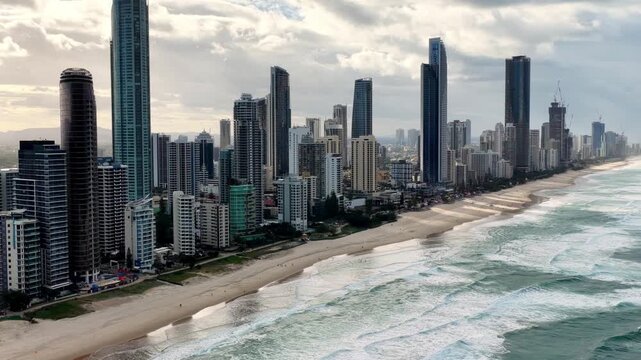 Towers zoom in on Gold coast of Australian pacific coast waterfront city in aerial view.