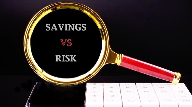 A close up look at a magnifying glass highlighting the critical phrase Savings vs Risk on a dark desk surface next to a keyboard