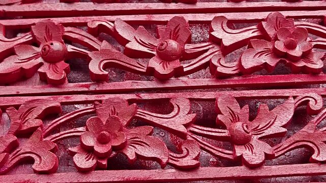 Close Up of Traditional Balinese Red Wood Carving with Intricate Floral Pattern