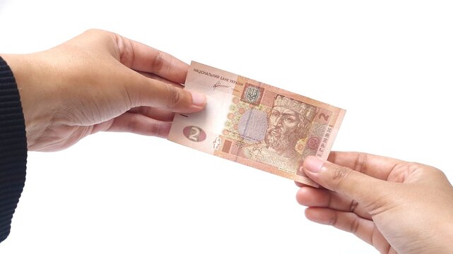 Woman holding a 2 Ukrainian hryvnia banknote with two hand, isolated on a white background. Currency, finance, cash payment, economy, and international money concept with copy space.