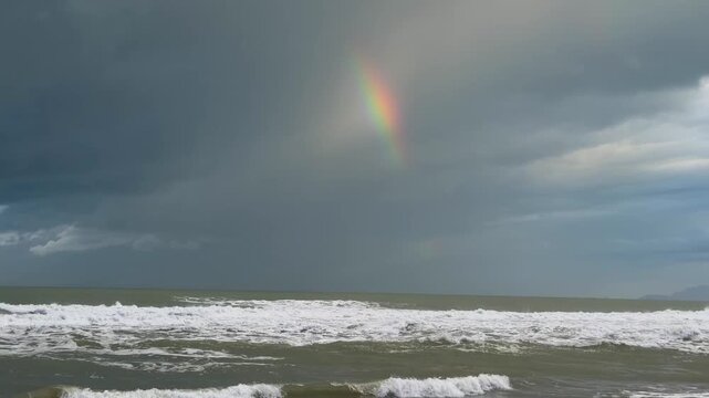 mare mosso con arcobaleno e surfista a viareggio in italia