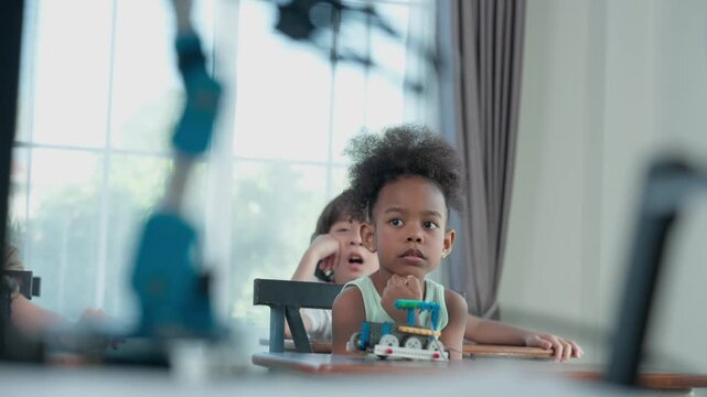 Young Engineers: multi ethnic Children engrossed in building and testing small robotics, showcasing curiosity, teamwork, and early STEM education. The focus robot and children hands-on engagement.
