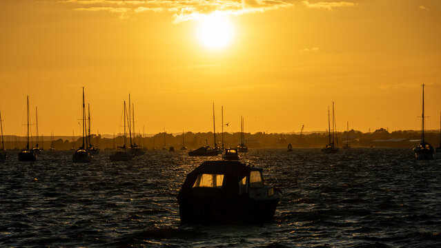 Calm waters and serene sunset over leisure boats at Sandbanks, Poole, Dorset near Bournemouth with foil surfers sailing through the wind.