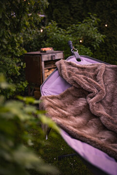 Hammock with fairy lights in the garden. Cozy evening atmosphere. Vertical background for relaxation and leisure outdoors.