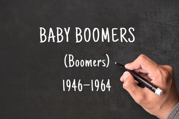 Fototapeta premium Baby Boomers written on blackboard with hand, Boomers born 1946 to 1964, generational demographics and social research concept