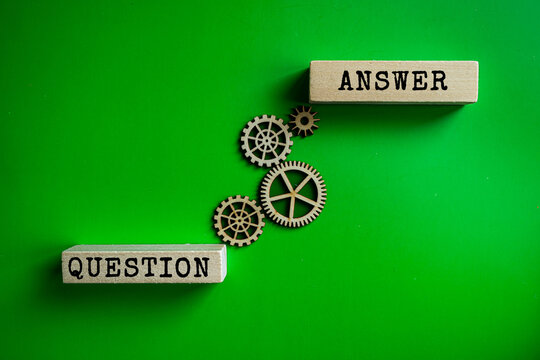 Question and Answer wooden labels with gears on green background, business knowledge management and information exchange concept