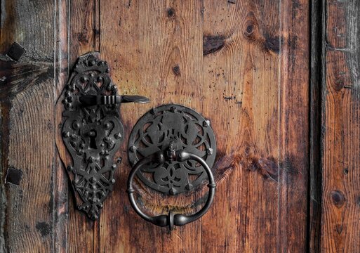 Forged door handle and knocker on an old wooden door, Austria