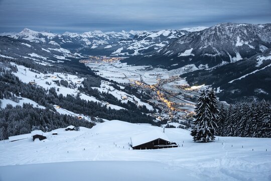 View of the Brixental valley in winter at dusk, snow-covered mountain huts in front, Hochbrixen, Brixen im Thale, Tyrol, Austria