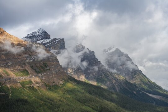 Three mountain peaks covered in fog, mountain range in Banff National Park, Alberta, Canada
