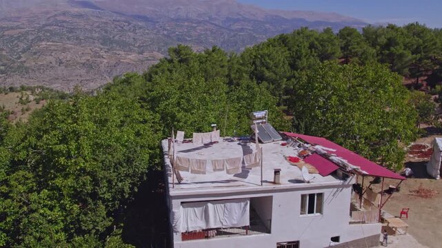 Aerial view of people sun-drying handmade food sheets on a rooftop, showing traditional rural food preparation, summer preservation, community work, and authentic daily life in a warm village setting.