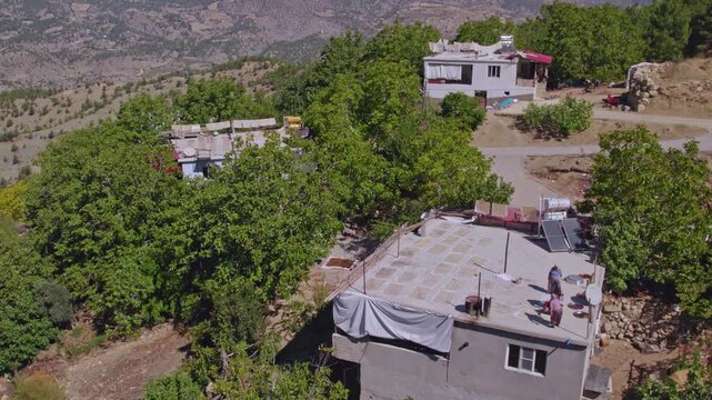 Aerial view of people sun-drying handmade food sheets on a rooftop, showing traditional rural food preparation, summer preservation, community work, and authentic daily life in a warm village setting.