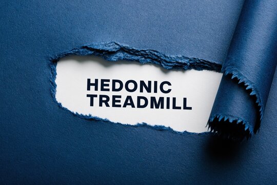 Hedonic Treadmill psychological theory under a torn blue paper surface