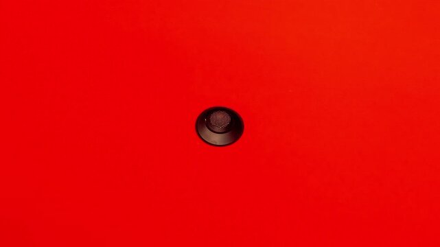 Cinematic zoom out footage of a single recessed downlight on bright red ceiling with minimalist interior composition.
