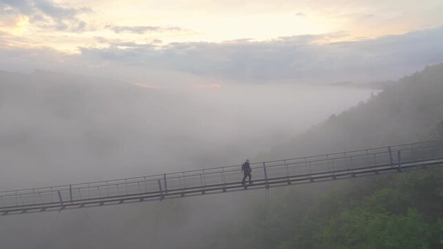 Fog covers Mosel Valley as a person walks on the Geierlay Bridge during early morning
