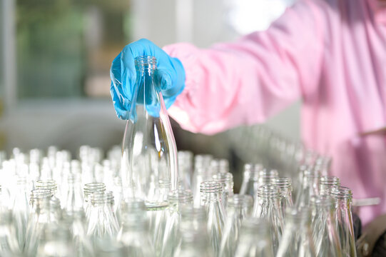 Focused industrial worker checking the quality and cleanliness of containers in a modern food manufacturing facility.
