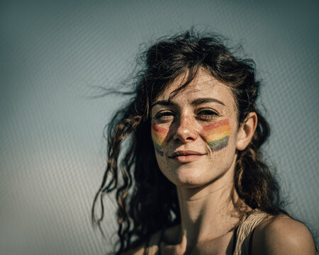 person painting small rainbow flag on cheek
