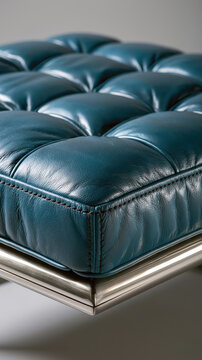 Tufted teal leather cushioning with visible stitching resting on a shiny metal frame, presenting a detailed view of luxurious and classic design aesthetic