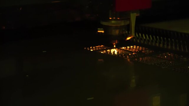 Industrial footage of a high-precision fiber laser cutting machine engraving and cutting a metal plate with intense sparks.
