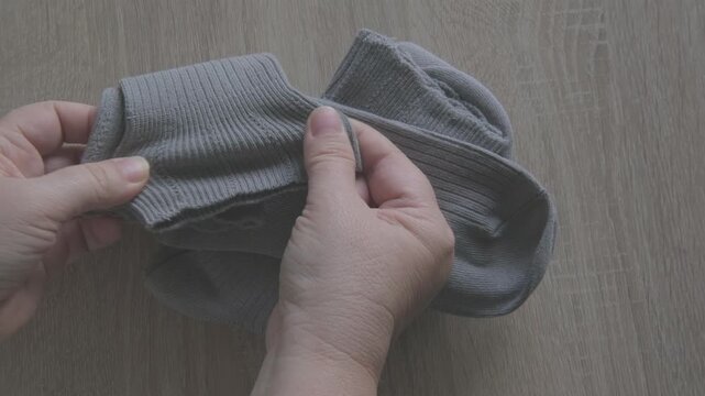 Female hands check cotton socks for quality, meticulous inspection footwear, Elastic bands and fabric texture. Diabetic-friendly apparel. Clothing purchase