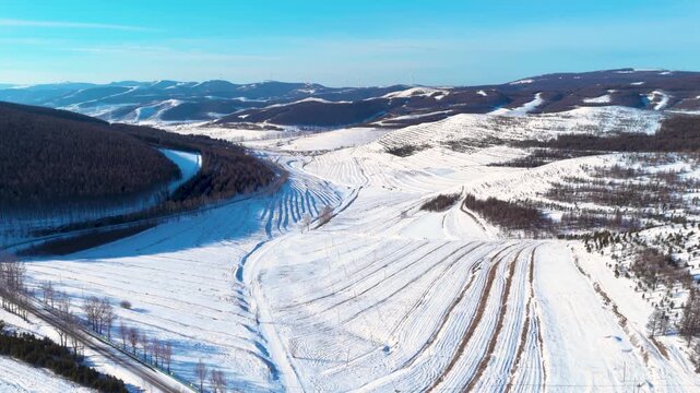Snowy Mountain Valley with Forest and Distant Wind Farm
