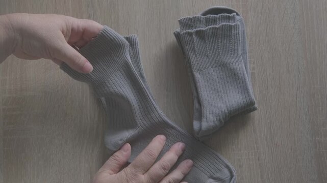 Female hands check cotton socks for quality, meticulous inspection footwear, Elastic bands and fabric texture. Diabetic-friendly apparel. Clothing purchase