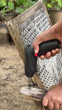 Close-up video of a cordless drill driving a screw into a wooden chair armrest while operating in low battery mode, showing DIY repair, woodworking, home maintenance, and power tool usage.