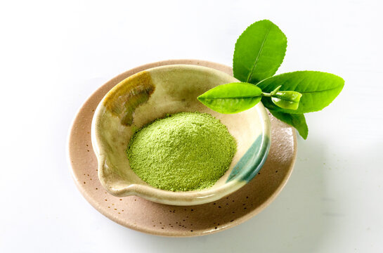 Bowl with powdered matcha tea on white background