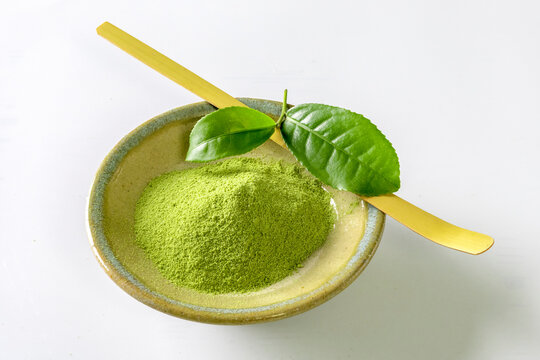 Bowl with powdered matcha tea on white background