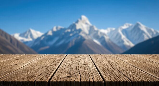 Rustic wooden table surface foreground with blurred snowy mountain peaks under a clear blue sky, perfect for product display and mockup, altitude, snow, texture