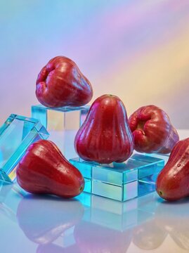 Fresh wax apples arranged on glass blocks with a colorful gradient background