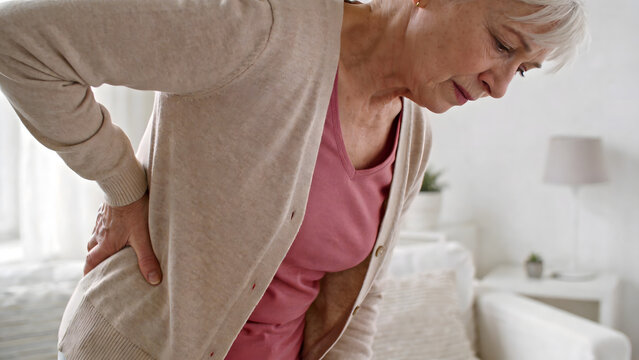 Elderly woman holding her back in pain