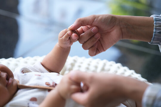 A mother plays with her baby. their hands held each other gently. Immortalize love, protection and new life in a loving embrace.

