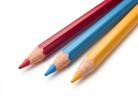 Three colored pencils arranged on white surface angled close up