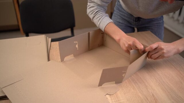 Top view of woman assembling cardboard box for shipping orders and parcels in e-commerce business. Small business