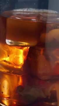 Close up of pouring milk over a coffee brew with ice cubes
