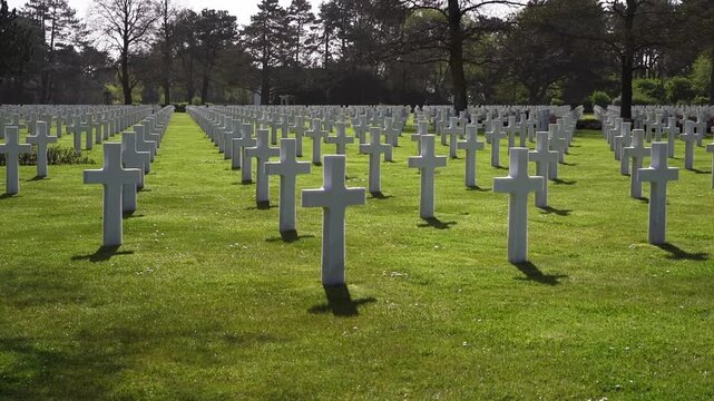 Military memorial cemetery with repeating rows of white grave markers. Honoring fallen soldiers