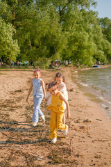 Obraz premium Three funny laughing girls are running along the coast by the sea. A warm summer day on vacation