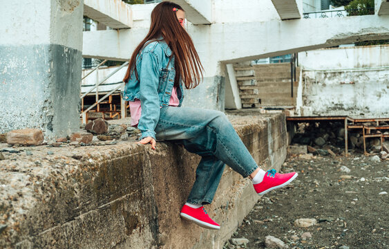Girl jumping off a concrete wall by the sea during summer vacation