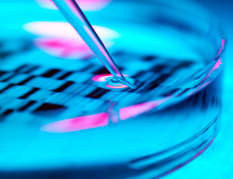 Close up of a pipette and petri dish over a DNA profile