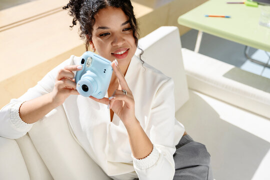 Smiling photographer holding light blue instant camera indoors