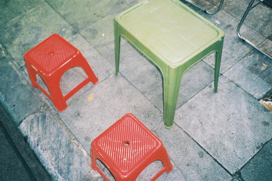 Red plastic stool and green table on a street in Vietnam