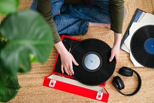 Placing a vinyl record on a vintage turntable indoors for relaxation