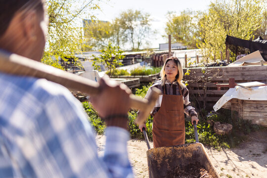 Gardeners working with wheelbarrow and tool in a community garden