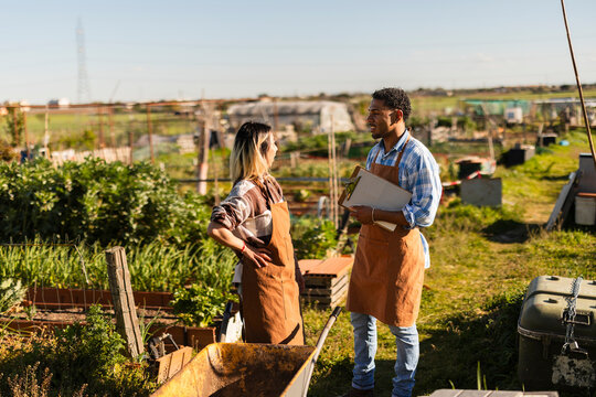 Gardeners in aprons talking with clipboard at allotment