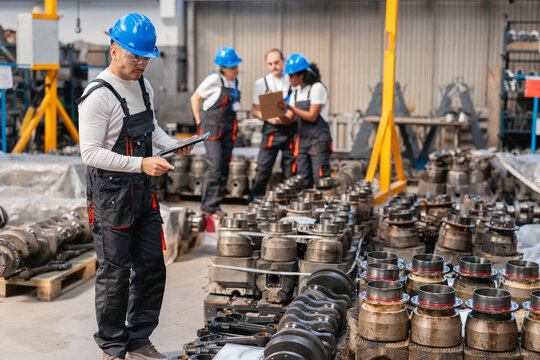 Engineer inspecting machinery with tablet in factory